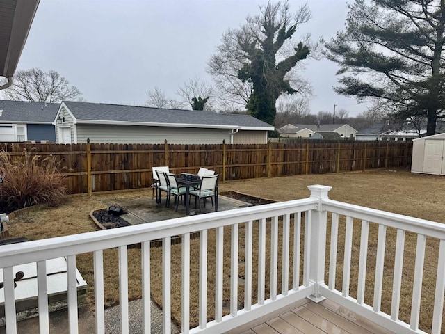 wooden deck with a storage shed, a fenced backyard, and an outbuilding