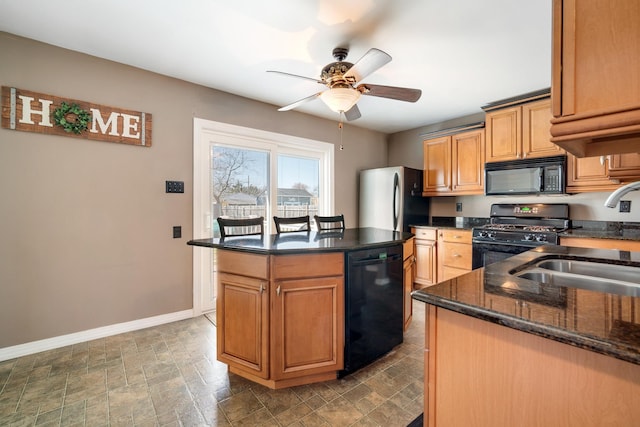 kitchen featuring stone finish floor, baseboards, a sink, ceiling fan, and black appliances