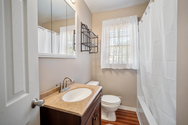 bathroom with toilet, vanity, baseboards, and wood finished floors