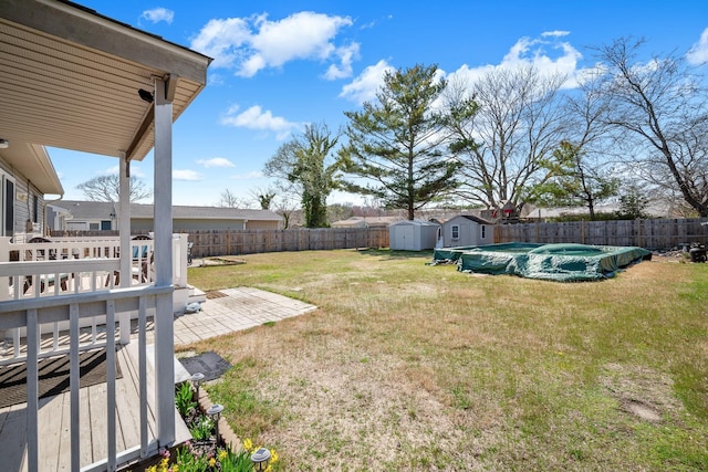 view of yard with a storage shed, a fenced in pool, a fenced backyard, an outbuilding, and a patio area