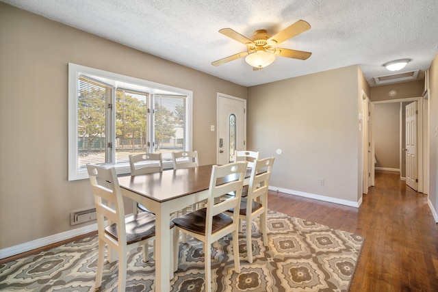 dining area with a textured ceiling, visible vents, baseboards, ceiling fan, and wood finished floors
