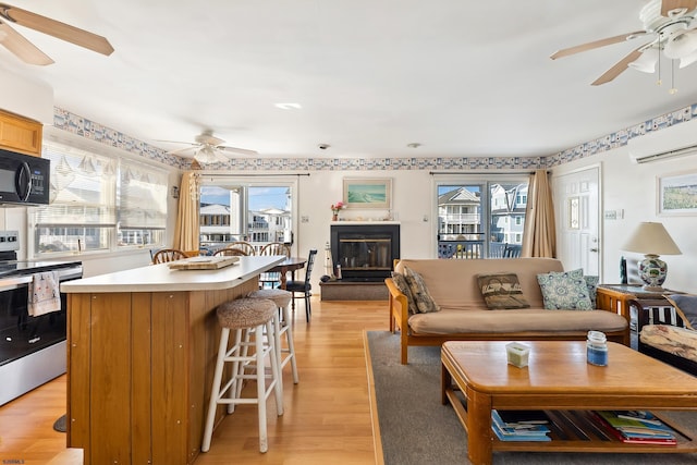 living room featuring light hardwood / wood-style flooring, an AC wall unit, and ceiling fan