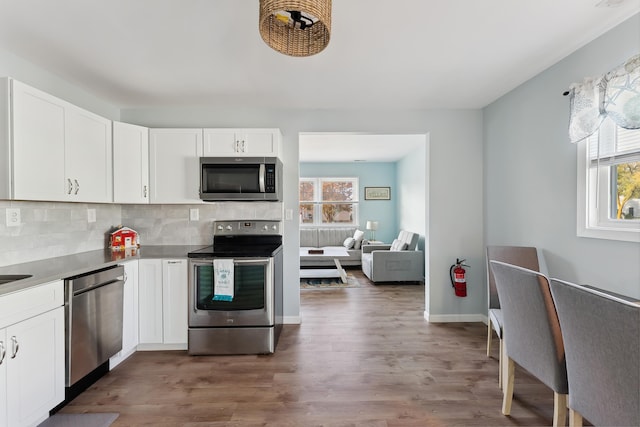 kitchen featuring white cabinets, appliances with stainless steel finishes, backsplash, and a wealth of natural light