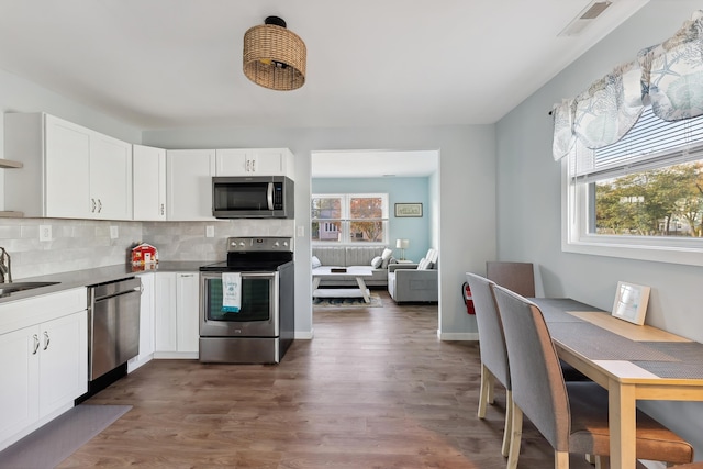 kitchen with white cabinets, backsplash, sink, and stainless steel appliances