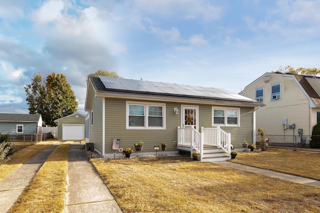 bungalow featuring solar panels, a garage, and an outbuilding