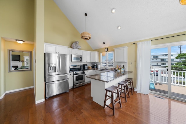 kitchen with stainless steel appliances, visible vents, white cabinets, a peninsula, and a kitchen bar