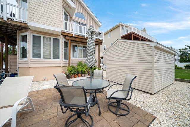 view of patio / terrace with an outbuilding, a storage shed, outdoor dining area, and a balcony