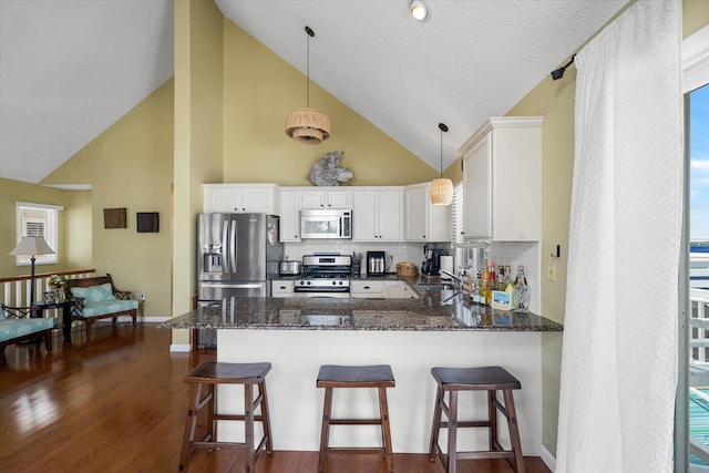 kitchen with dark stone counters, stainless steel appliances, a sink, and white cabinetry