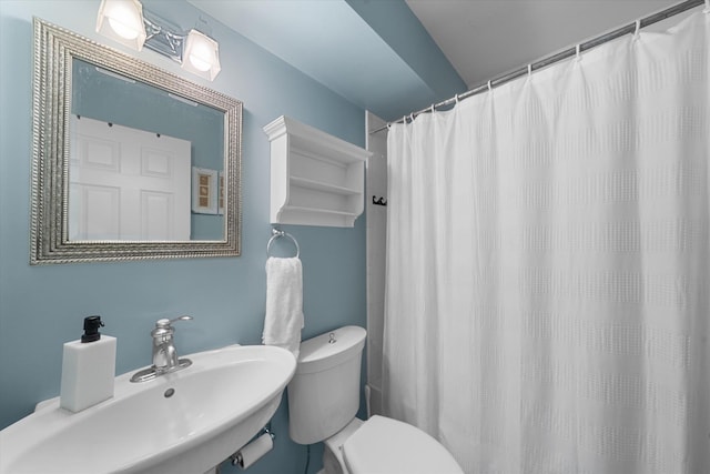 full bathroom featuring toilet, curtained shower, and a sink