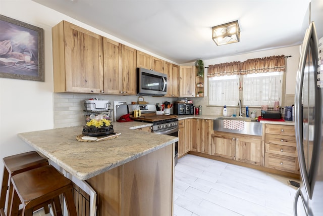 kitchen featuring backsplash, stainless steel appliances, a sink, and a peninsula