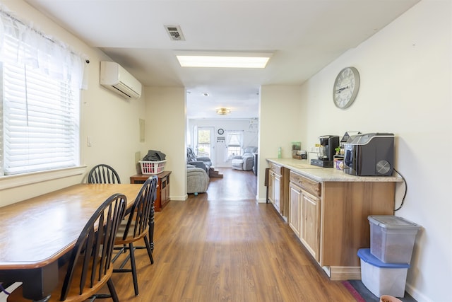 kitchen featuring visible vents, wood finished floors, baseboards, light countertops, and a wall mounted AC