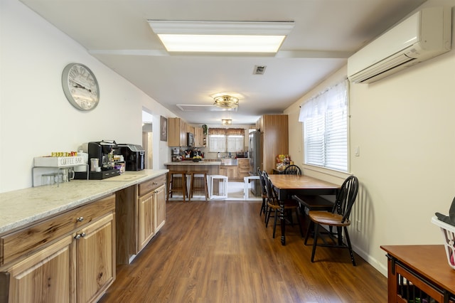 kitchen with brown cabinets, a wall mounted AC, visible vents, and dark wood-type flooring