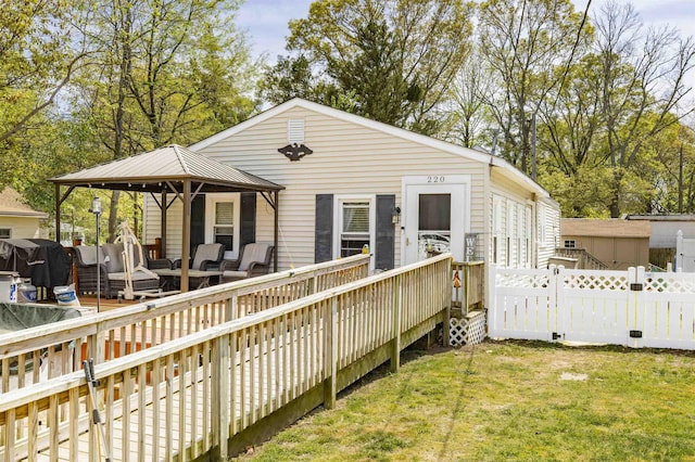 rear view of house with a deck, a gazebo, fence, a yard, and outdoor lounge area