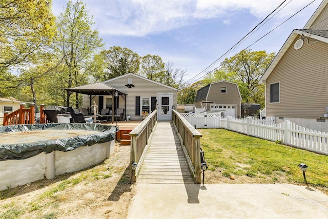 rear view of house with a garage, a lawn, fence, a wooden deck, and a gazebo