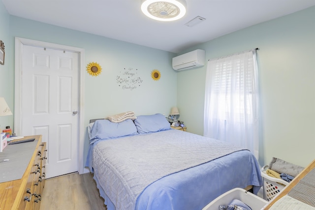 bedroom featuring light wood-style floors and a wall mounted AC