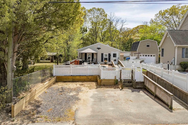 view of front of property featuring fence private yard, a wooden deck, an outbuilding, and a detached garage