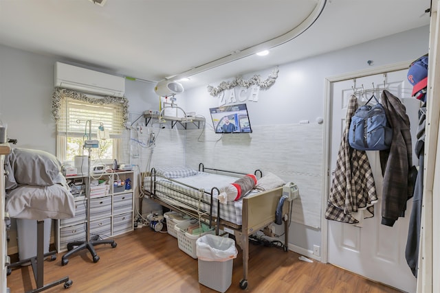 bedroom featuring wood finished floors and a wall unit AC