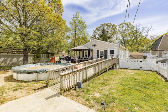 rear view of house featuring a gazebo, a fenced backyard, a yard, a patio, and a covered pool