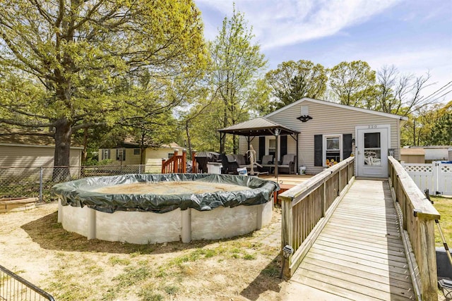 rear view of property featuring a deck, a gazebo, a fenced in pool, and fence