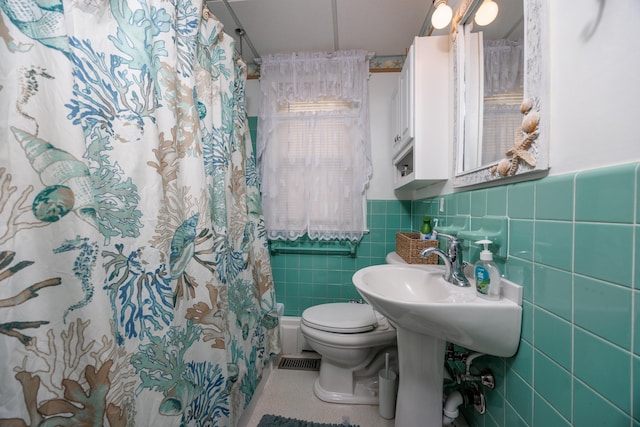 full bath with toilet, wainscoting, tile walls, and a shower with shower curtain