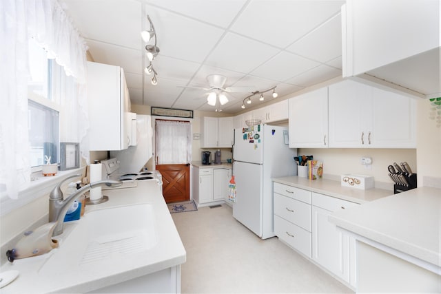 kitchen featuring white appliances, a sink, white cabinets, light countertops, and track lighting