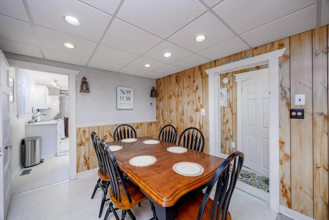 dining area featuring a paneled ceiling, wooden walls, and recessed lighting