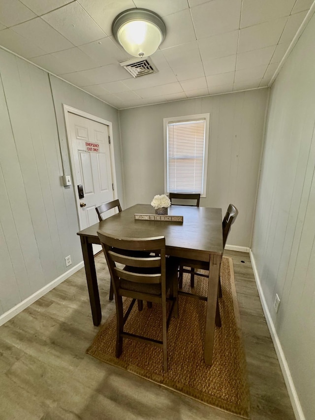 dining room featuring wood finished floors, baseboards, and wooden walls