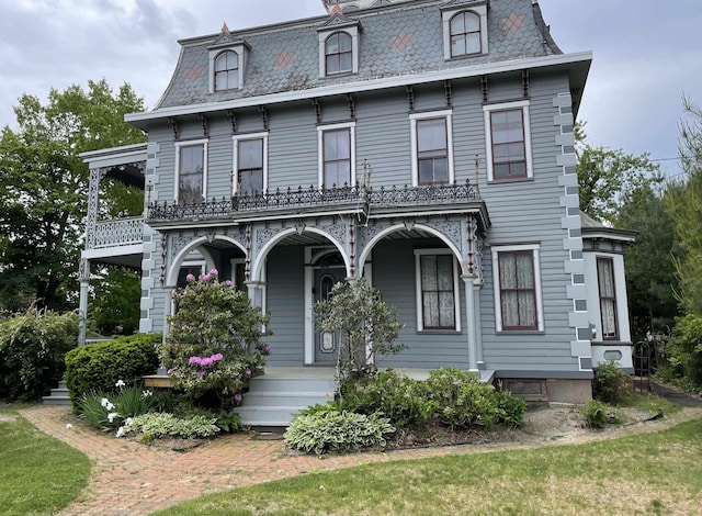 second empire-style home with a porch, mansard roof, and a high end roof