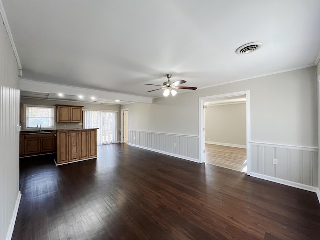 unfurnished living room featuring sink, crown molding, dark hardwood / wood-style floors, and ceiling fan