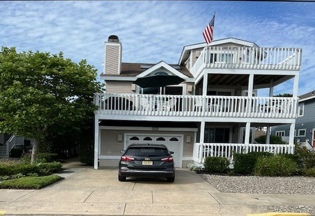 53 E 25th St, Avalon, NJ 08202 - view of front of house with a balcony, concrete driveway, an attached garage, a chimney, and a porch