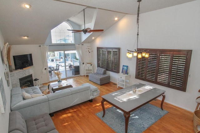 living room with high vaulted ceiling, ceiling fan with notable chandelier, and hardwood / wood-style flooring