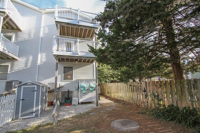 rear view of property featuring a balcony, central AC unit, and a storage unit