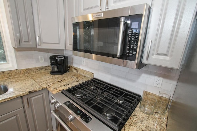 kitchen with white cabinets, decorative backsplash, and appliances with stainless steel finishes