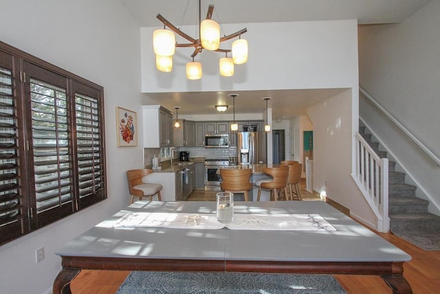 dining space featuring hardwood / wood-style floors, a high ceiling, a notable chandelier, and sink