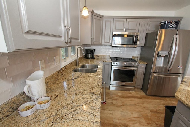 kitchen featuring sink, gray cabinets, appliances with stainless steel finishes, tasteful backsplash, and decorative light fixtures