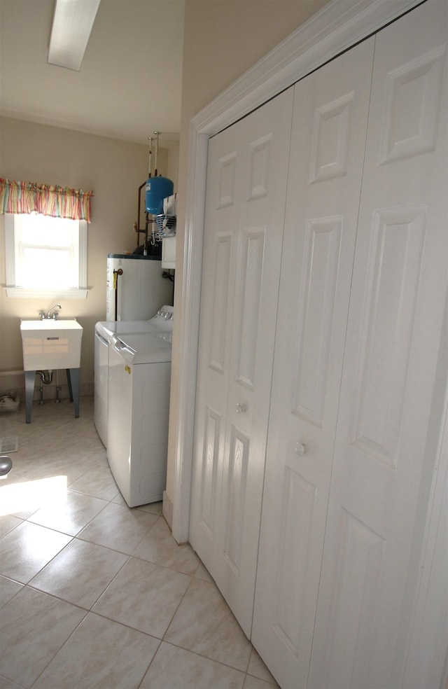 laundry area featuring sink, light tile patterned floors, washing machine and dryer, and water heater