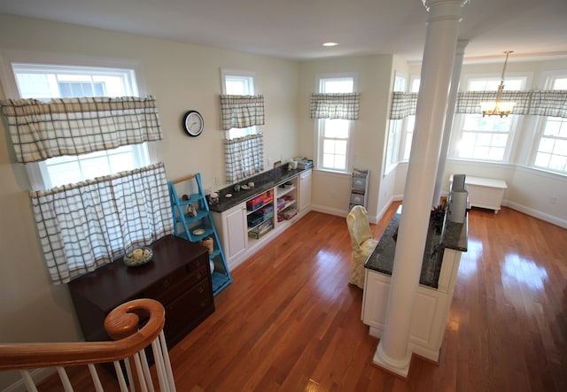 living room featuring hardwood / wood-style flooring, ornate columns, and an inviting chandelier