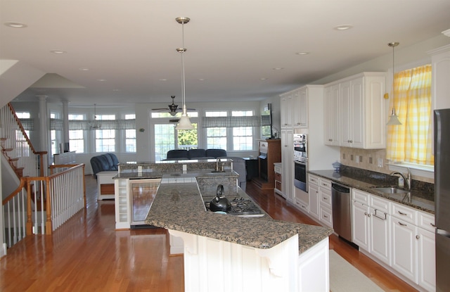 kitchen with white cabinetry, sink, wine cooler, decorative light fixtures, and appliances with stainless steel finishes