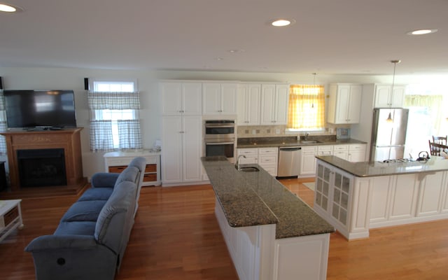 kitchen with sink, a center island, decorative light fixtures, white cabinets, and appliances with stainless steel finishes