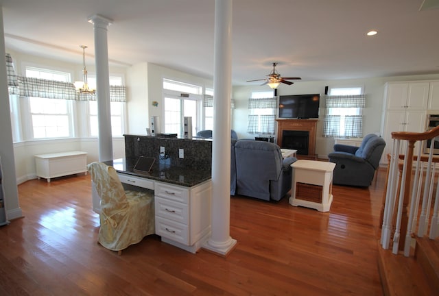 kitchen with dark hardwood / wood-style flooring, dark stone counters, ceiling fan with notable chandelier, decorative light fixtures, and white cabinetry