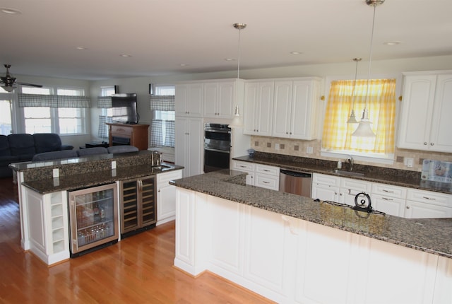 kitchen with white cabinets, decorative light fixtures, dishwasher, and beverage cooler