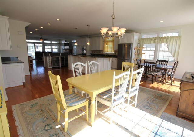 dining area featuring ceiling fan with notable chandelier, hardwood / wood-style flooring, and a healthy amount of sunlight