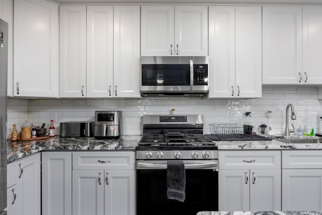 kitchen with tasteful backsplash, sink, white cabinets, and stainless steel appliances