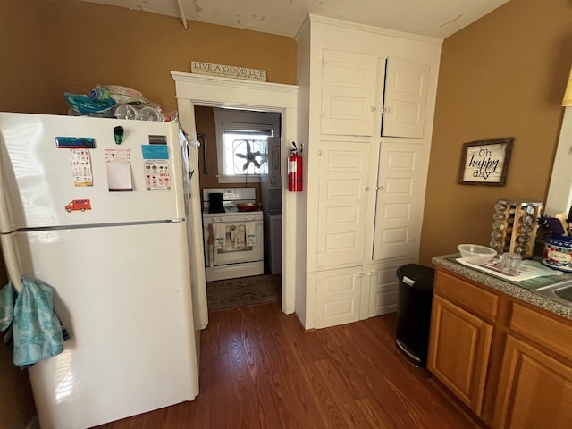 kitchen featuring dark wood finished floors, white appliances, and brown cabinets