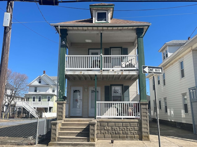 view of front of home featuring roof with shingles, a porch, and fence