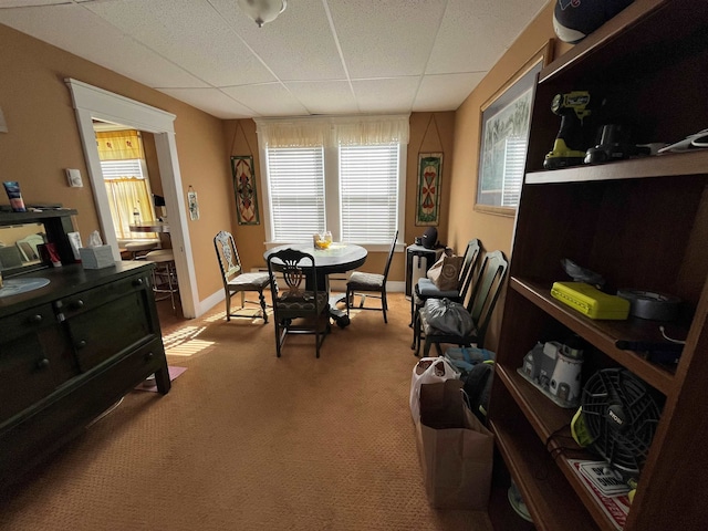 dining area with baseboards, a paneled ceiling, and light colored carpet