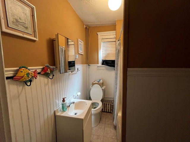 full bath with toilet, radiator heating unit, wainscoting, tile patterned flooring, and vanity