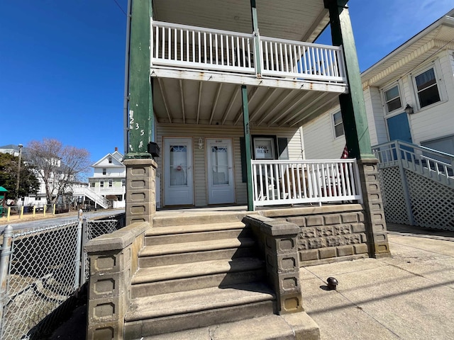 view of exterior entry with a balcony and a porch