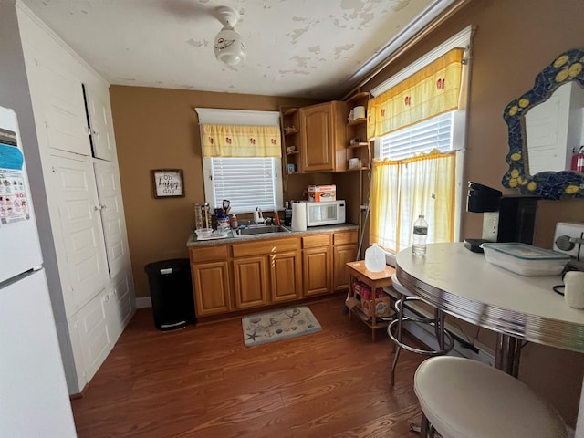 kitchen featuring a sink, brown cabinets, dark wood-style floors, white appliances, and open shelves