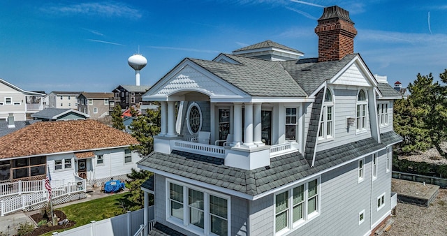 rear view of property featuring a chimney, fence, and a balcony